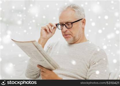 people, vision and mass media concept - senior man in glasses reading newspaper over snow. senior man in glasses reading newspaper over snow