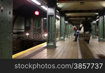 People wait as the subway train arrives at the station