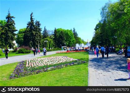 people walking along the park. people have a rest in the city park with beds of tulips in the spring