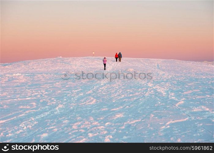 People walking at sunset in winter mountains covered with snow.