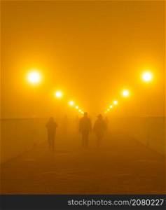 People walking by Tioschin Bridge in the fog at night. Odessa, Ukraine