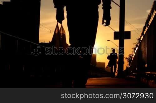 people walking on a bridge at sunset