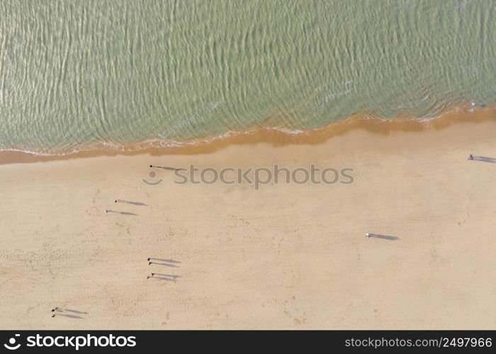 People walking on a north sea sandy beach, aerial drone view