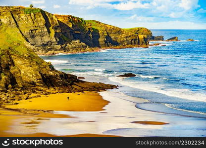 People walking on Carniciega beach, Asturias coast. Seaside landscape in northern Spain.. Asturias coast with Carniciega beach in Spain.