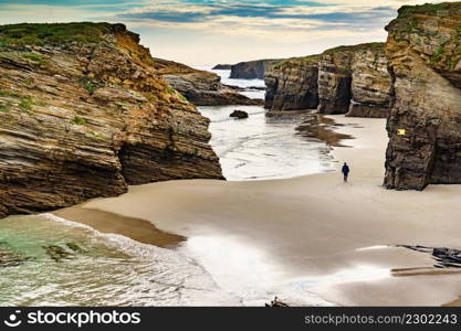 People walking on Cathedrals Beach at low tide, Playa las Catedrales in Ribadeo, province of Lugo, Galicia. Cantabric coast in northern Spain. Tourist place.. People walking on Beach Cathedrals Beach, Galicia Spain.