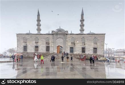 People walking on stairs of New mosque on a snowy day in winter.Istanbul,Turkey,18,January 2016. People walking on stairs of New mosque on a snowy day