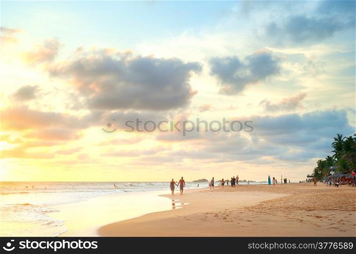 People walking on the beach of Sri Lanka at sunset
