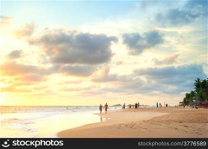 People walking on the beach of Sri Lanka at sunset
