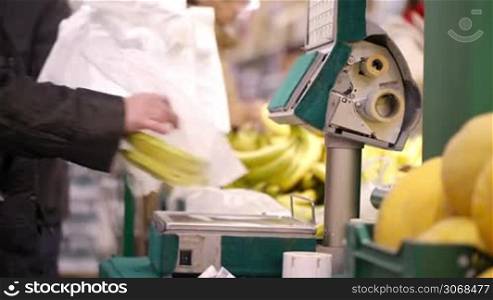People weighing bananas one after another. Self-service in the supermarket using electronic scales.