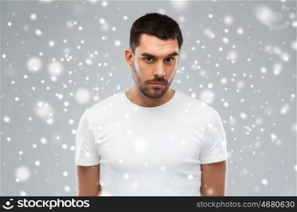 people, winter and christmas concept concept - young man portrait over snow on gray background