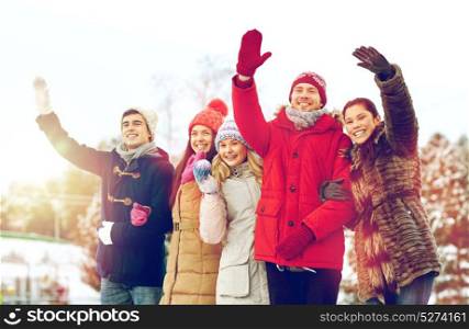 people, winter and friendship concept - happy friends waving hands in winter park. happy friends waving hands outdoors