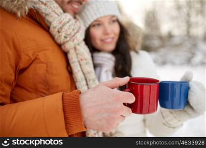 people, winter, drinks and season concept - close up of happy couple holding hot tea cups