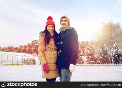 people, winter, friendship, love and leisure concept - happy couple ice skating on rink outdoors. happy couple ice skating on rink outdoors
