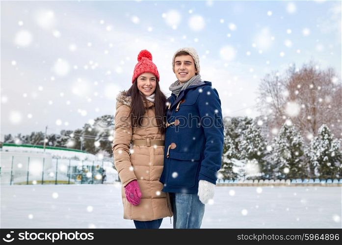 people, winter, friendship, love and leisure concept - happy couple ice skating on rink outdoors