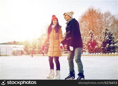 people, winter, friendship, sport and leisure concept - happy couple ice skating on rink outdoors. happy couple ice skating on rink outdoors