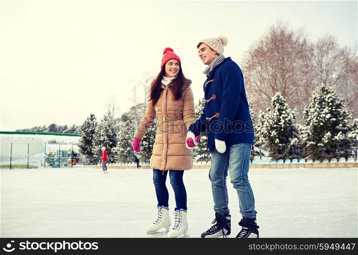 people, winter, friendship, sport and leisure concept - happy couple ice skating on rink outdoors