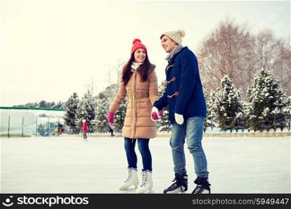 people, winter, friendship, sport and leisure concept - happy couple ice skating on rink outdoors