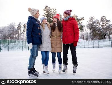 people, winter, friendship, sport and leisure concept - happy friends ice skating and hugging on rink outdoors