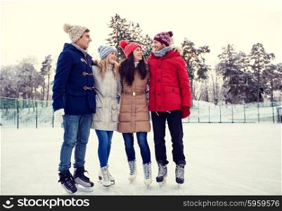 people, winter, friendship, sport and leisure concept - happy friends ice skating and hugging on rink outdoors