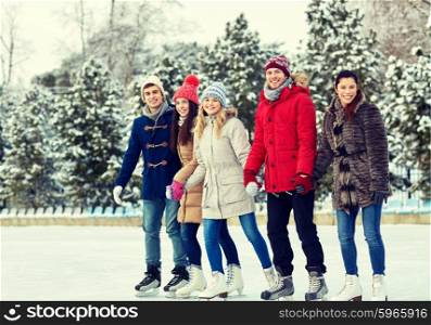 people, winter, friendship, sport and leisure concept - happy friends ice skating and holding hands on rink outdoors