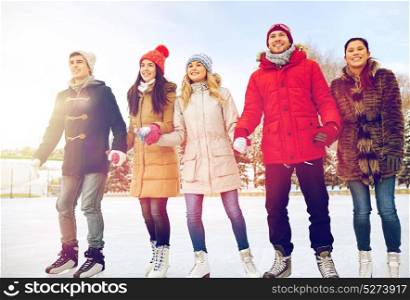people, winter, friendship, sport and leisure concept - happy friends ice skating on rink outdoors. happy friends ice skating on rink outdoors