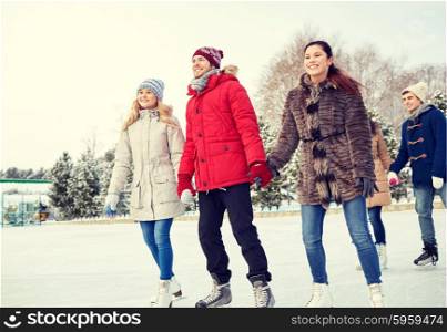 people, winter, friendship, sport and leisure concept - happy friends ice skating on rink outdoors