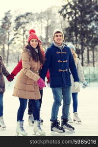 people, winter, friendship, sport and leisure concept - happy friends ice skating on rink outdoors