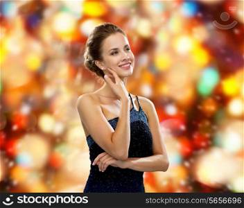 people, winter holidays, christmas and glamour concept - smiling woman in evening dress over black background over red lights background