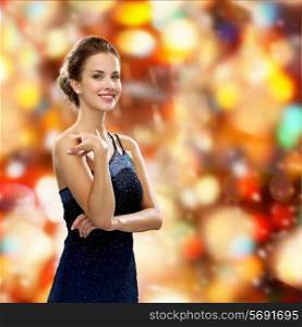 people, winter holidays, christmas and glamour concept - smiling woman in evening dress over red lights background