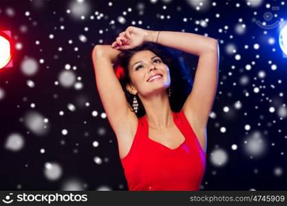 people, winter holidays, disco, night lifestyle and leisure concept - beautiful sexy woman in red dress dancing at nightclub over snow