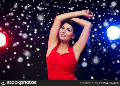 people, winter holidays, disco, night lifestyle and leisure concept - beautiful sexy woman in red dress dancing at nightclub over snow