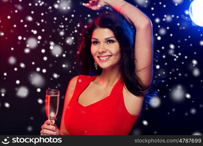 people, winter holidays, party, night lifestyle and leisure concept - beautiful sexy woman in red dress with champagne glass dancing at nightclub over snow