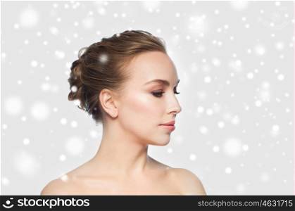 people, winter, plastic surgery and beauty concept - beautiful young woman face over gray background and snow