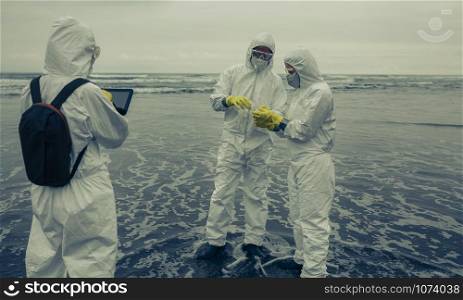 People with bacteriological protection suits analyzing seawater on the beach. People with protection suits analyzing seawater