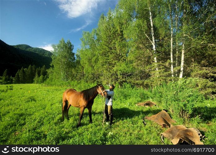 People with horses. Horses walk and graze.. Orlov village, Altai, Russia - June 29, 2016: People with horses Horses walk and graze