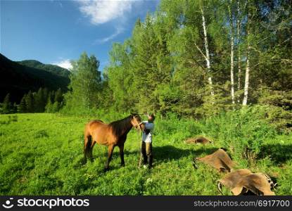 People with horses. Horses walk and graze.. Orlov village, Altai, Russia - June 29, 2016: People with horses Horses walk and graze