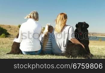 People with Newfoundland dogs resting on the nature, rear view