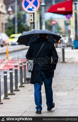 People with umbrella on the street on a rainy day in Bucharest, Romania, 2021