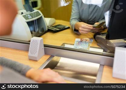 people, withdrawal, money, saving and finance concept - clerk counting swiss francs cash at bank office or currency exchanger. clerk counting cash money at bank office