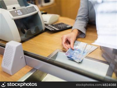 people, withdrawal, money, saving and finance concept - clerk with swiss francs cash at bank office or currency exchanger