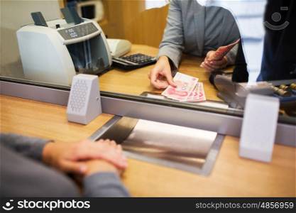 people, withdrawal, saving and finance concept - clerk counting cash money for customer at bank office or currency exchanger