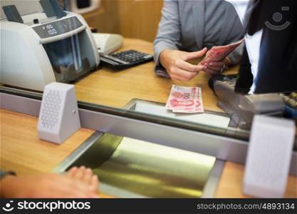 people, withdrawal, saving and finance concept - clerk counting cash money for customer at bank office or currency exchanger