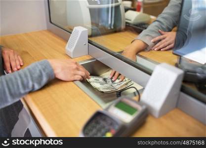 people, withdrawal, saving and finance concept - clerk giving cash money to customer at bank office or currency exchanger