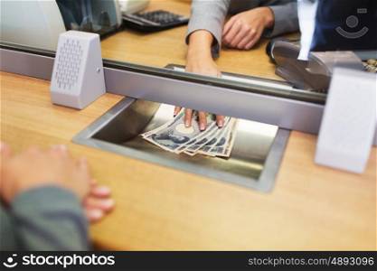 people, withdrawal, saving and finance concept - clerk giving cash money to customer at bank office or currency exchanger