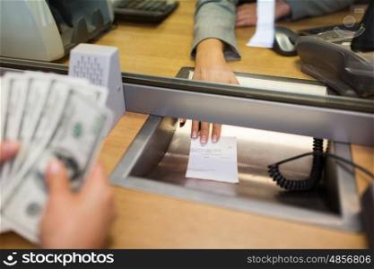 people, withdrawal, saving and finance concept - clerk giving receipt to customer with money at bank office or currency exchanger