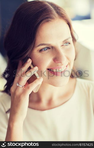 people, women, business and lifestyle concept - happy woman calling on smart phone at restaurant