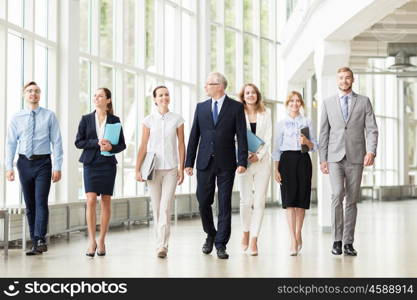 people, work and corporate concept - business team with folders walking along office building and talking