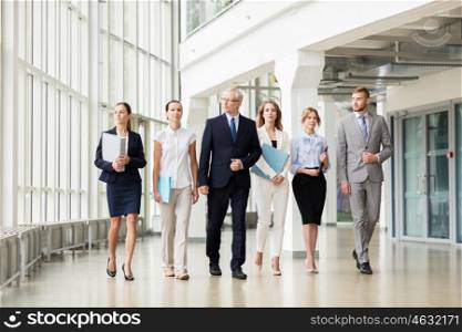 people, work and corporate concept - business team with folders walking along office building and talking