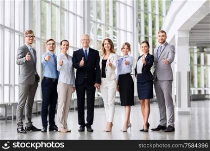 people, work and corporate concept - happy business team showing thumbs up at office. business people showing thumbs up at office