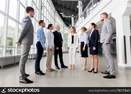 people, work and corporate concept - happy business team talking at office building. business people talking at office building